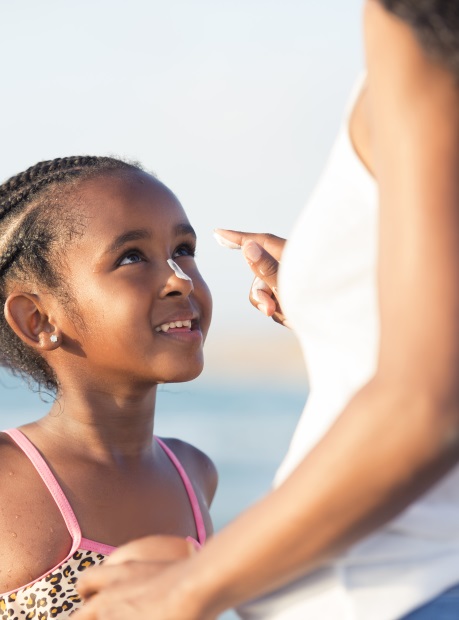Mother applying sun protection to her 6 years daughter in the beach.